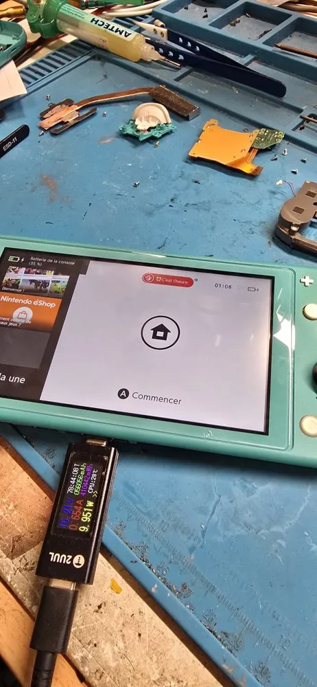 Nintendo Switch Lite en test après réparation, avec testeur de charge